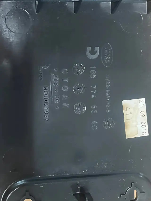 Black plastic part labeled with serial numbers for Roverland Parts Cupholder Assembly Center